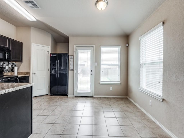 kitchen featuring light tile patterned floors, a wealth of natural light, lofted ceiling, and black appliances