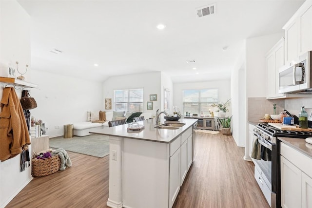 kitchen featuring appliances with stainless steel finishes, sink, a center island with sink, and white cabinets