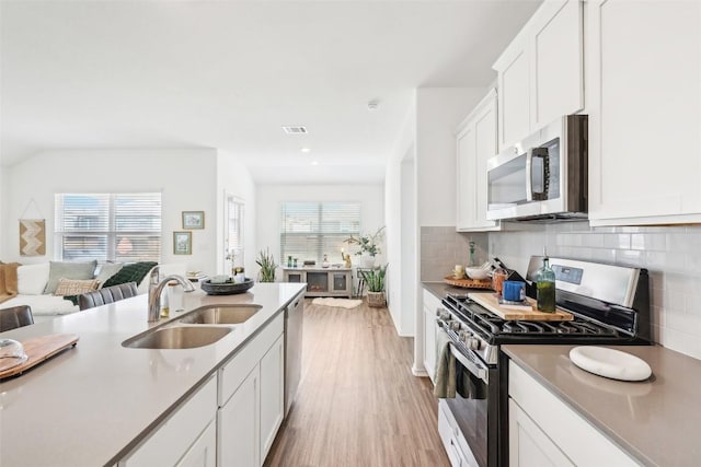 kitchen with sink, tasteful backsplash, light hardwood / wood-style flooring, appliances with stainless steel finishes, and white cabinets