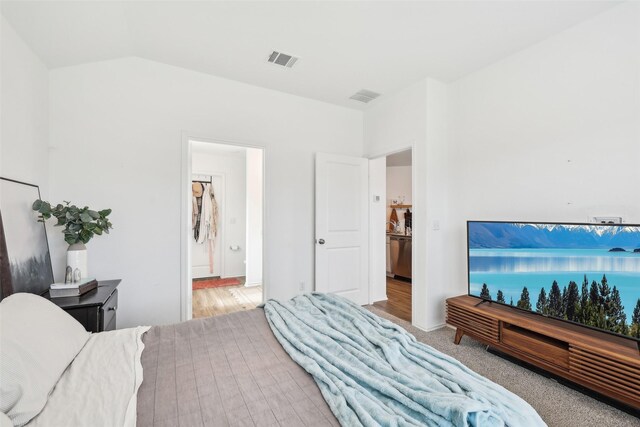 bedroom featuring light colored carpet and vaulted ceiling