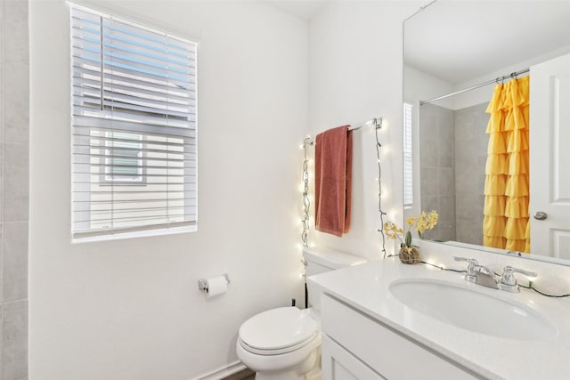 bathroom featuring vanity, plenty of natural light, toilet, and walk in shower