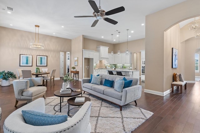 living room with ceiling fan with notable chandelier and dark hardwood / wood-style floors