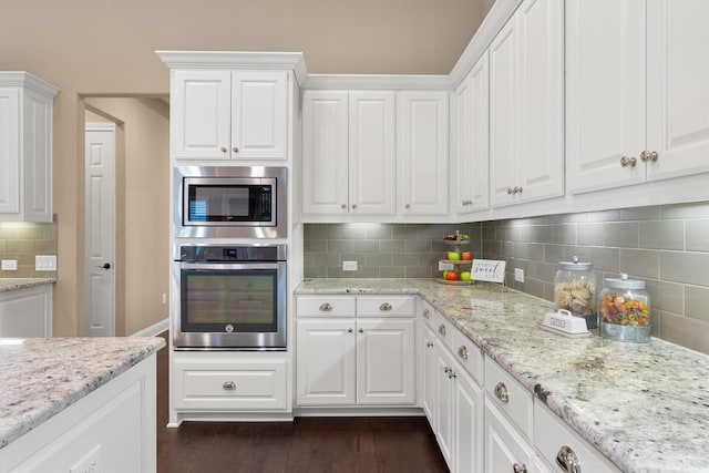 kitchen featuring dark hardwood / wood-style flooring, white cabinetry, appliances with stainless steel finishes, and tasteful backsplash