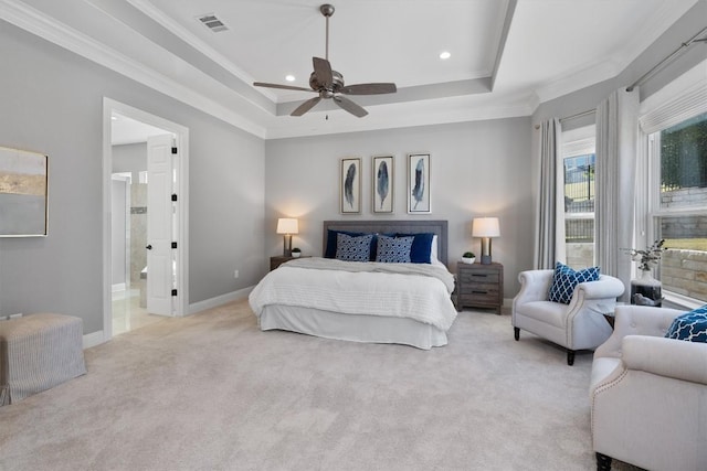 bedroom with a raised ceiling, ceiling fan, ornamental molding, connected bathroom, and light colored carpet