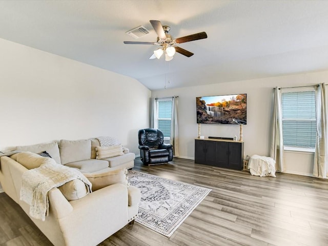 living area with baseboards, visible vents, a ceiling fan, lofted ceiling, and wood finished floors