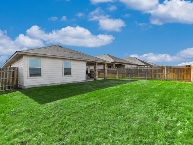 back of property with a fenced backyard and a yard