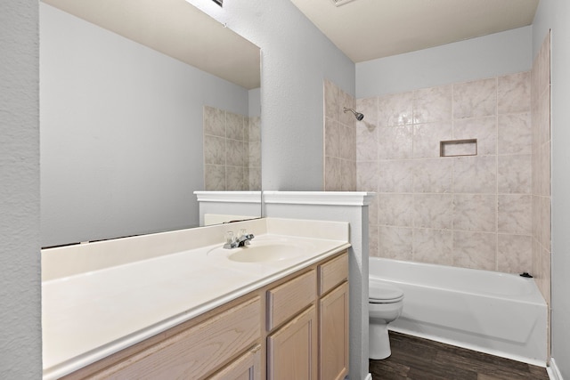 full bathroom featuring hardwood / wood-style floors, toilet, vanity, and tiled shower / bath combo