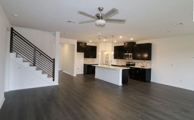 kitchen with tasteful backsplash, dark hardwood / wood-style flooring, an island with sink, and stainless steel appliances