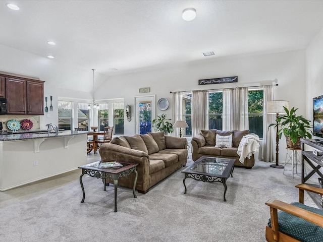 carpeted living room featuring a chandelier, a healthy amount of sunlight, and vaulted ceiling