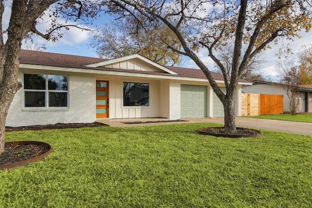 view of front of property with concrete driveway, an attached garage, board and batten siding, fence, and a front lawn