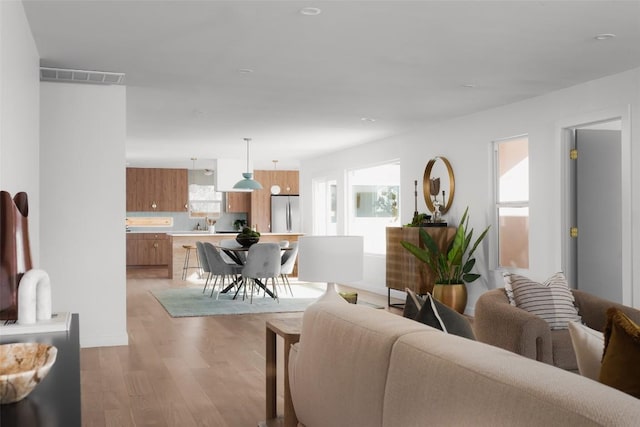 living room featuring light wood-type flooring, visible vents, and plenty of natural light