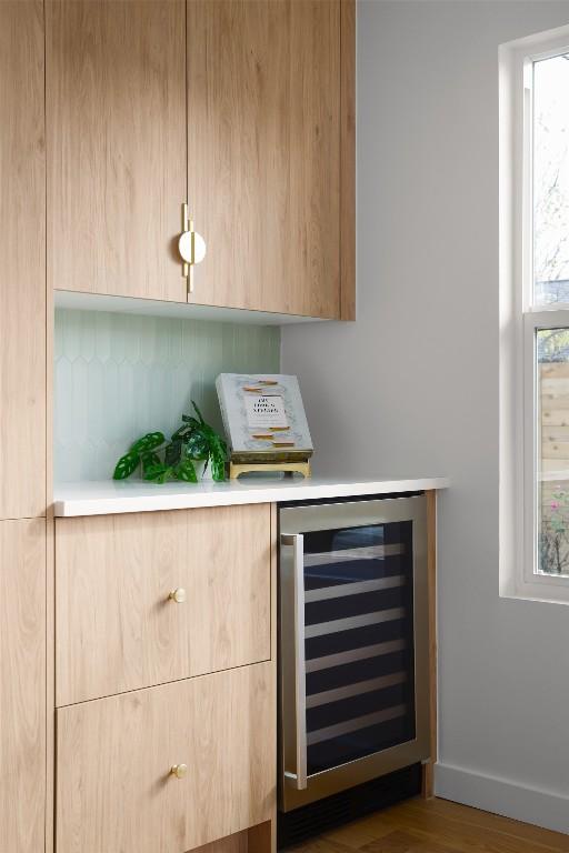 bar with hardwood / wood-style flooring, beverage cooler, and light brown cabinetry