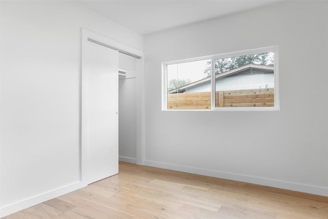 unfurnished bedroom featuring a closet, baseboards, and light wood finished floors