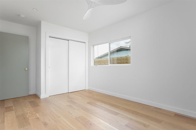 unfurnished bedroom featuring light wood finished floors, a ceiling fan, baseboards, and a closet