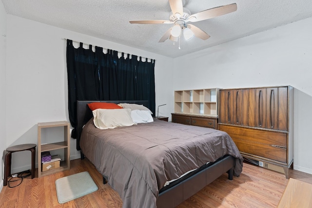 bedroom featuring ceiling fan, light wood-type flooring, and a textured ceiling