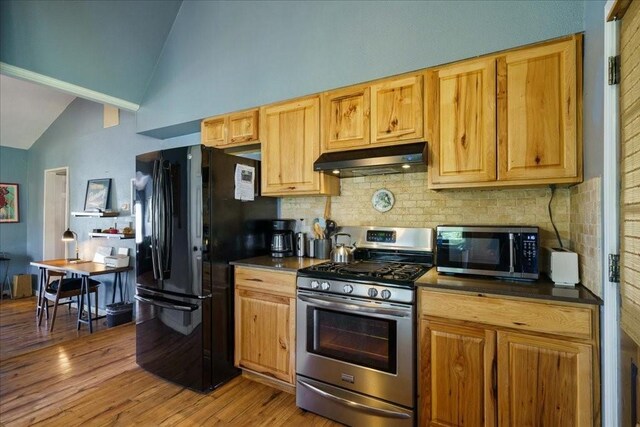 kitchen with decorative backsplash, high vaulted ceiling, light wood-type flooring, and appliances with stainless steel finishes