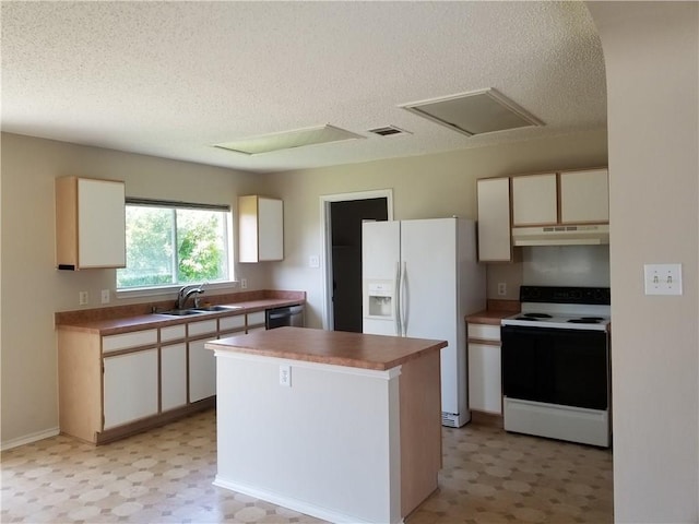 kitchen with a textured ceiling, white appliances, a kitchen island, and sink