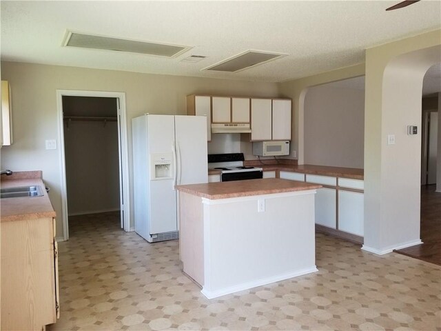 kitchen with white appliances, sink, a textured ceiling, a kitchen island, and white cabinetry