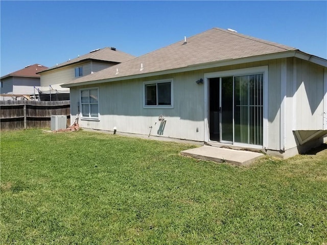 rear view of property with a yard and central air condition unit