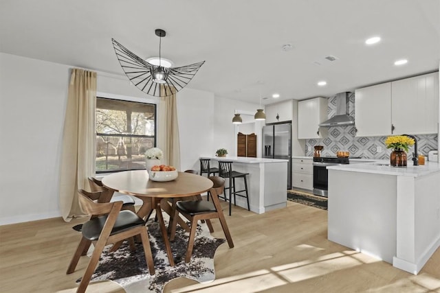 dining area with a notable chandelier, light wood-type flooring, and sink