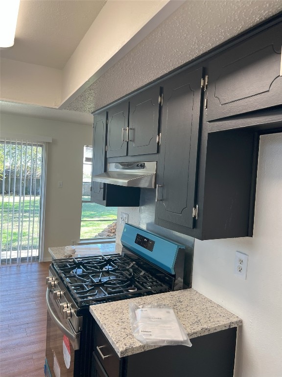 kitchen featuring light stone counters, stainless steel gas range oven, range hood, and dark hardwood / wood-style floors