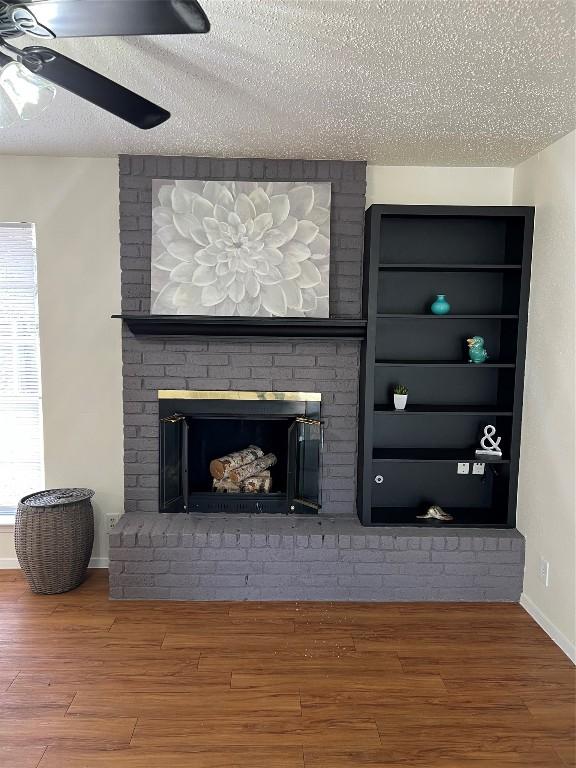 interior details featuring a textured ceiling, built in features, hardwood / wood-style flooring, ceiling fan, and a fireplace