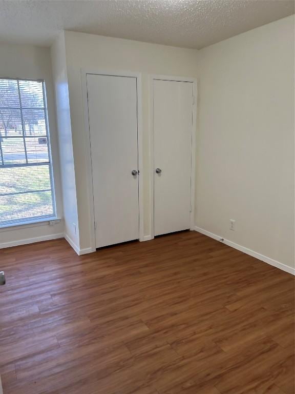 unfurnished bedroom with multiple closets, dark hardwood / wood-style flooring, and a textured ceiling