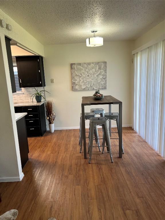 dining area featuring wood-type flooring and a textured ceiling