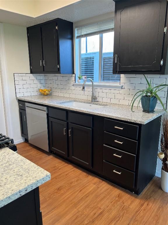 kitchen featuring decorative backsplash, dishwasher, sink, and light hardwood / wood-style flooring