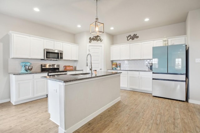 kitchen with white cabinetry, light wood-type flooring, stainless steel appliances, and an island with sink