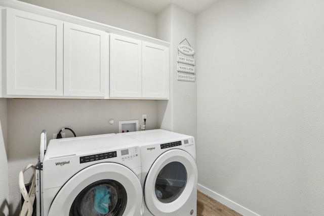 clothes washing area with hardwood / wood-style flooring, cabinets, and washing machine and dryer