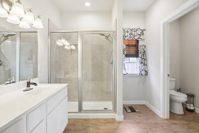 bathroom with a notable chandelier, wood-type flooring, toilet, vanity, and a shower with shower door