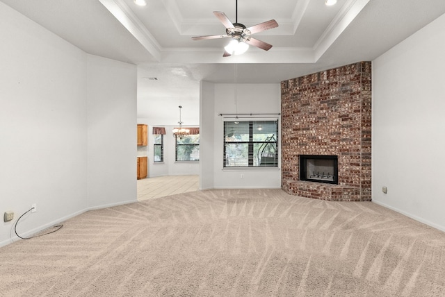 unfurnished living room featuring crown molding, a fireplace, and a tray ceiling