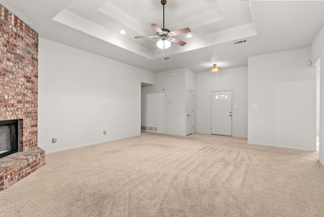 unfurnished living room with ceiling fan, light colored carpet, a fireplace, and a tray ceiling