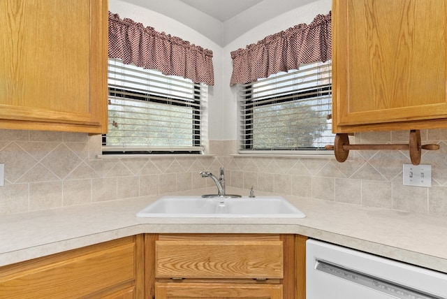 kitchen featuring backsplash, white dishwasher, and sink