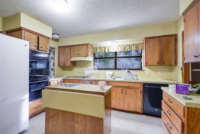 kitchen with a textured ceiling, sink, a center island with sink, and black appliances