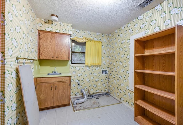 interior space with cabinets, a textured ceiling, and sink