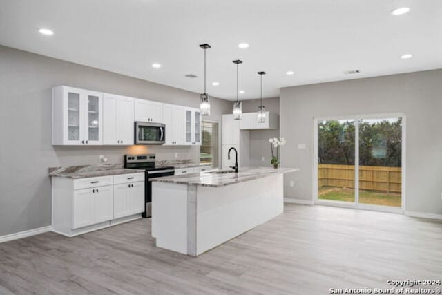 209 Filmore Fls, Cibolo, TX 78108 - kitchen with stainless steel appliances, a sink, light wood-style floors, light stone counters, and baseboards