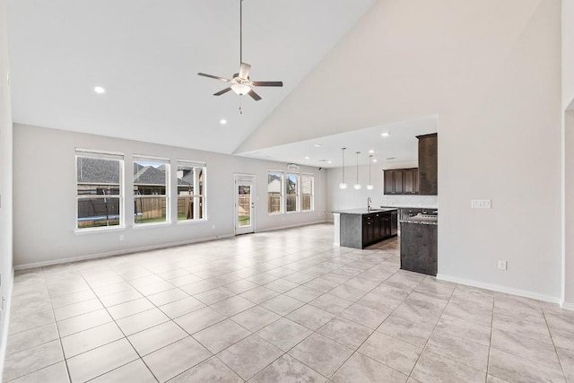 unfurnished living room featuring ceiling fan, sink, light tile patterned floors, and high vaulted ceiling