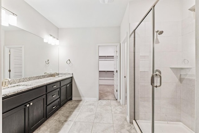 bathroom with a shower with door, vanity, and tile patterned flooring