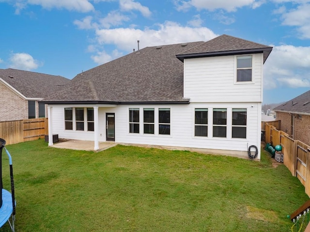 rear view of house with a yard, a trampoline, and a patio area