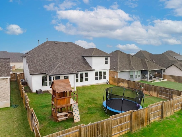 rear view of property with a playground, a trampoline, and a lawn