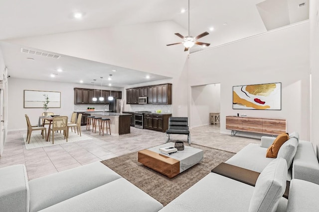 tiled living room featuring ceiling fan, sink, and high vaulted ceiling