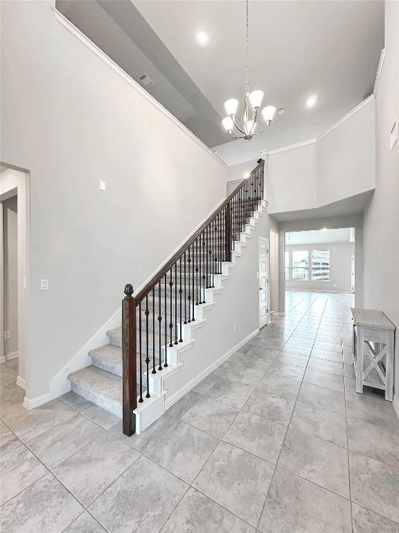 stairway with ornamental molding, tile patterned floors, and a chandelier