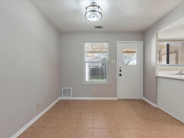 doorway featuring light tile patterned floors and a textured ceiling