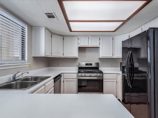 kitchen featuring sink, white cabinets, stainless steel appliances, and a textured ceiling