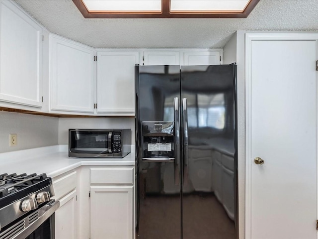 kitchen with a textured ceiling, white cabinetry, and black appliances