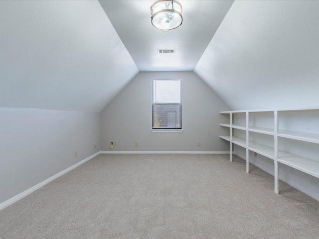 bonus room with light colored carpet and vaulted ceiling