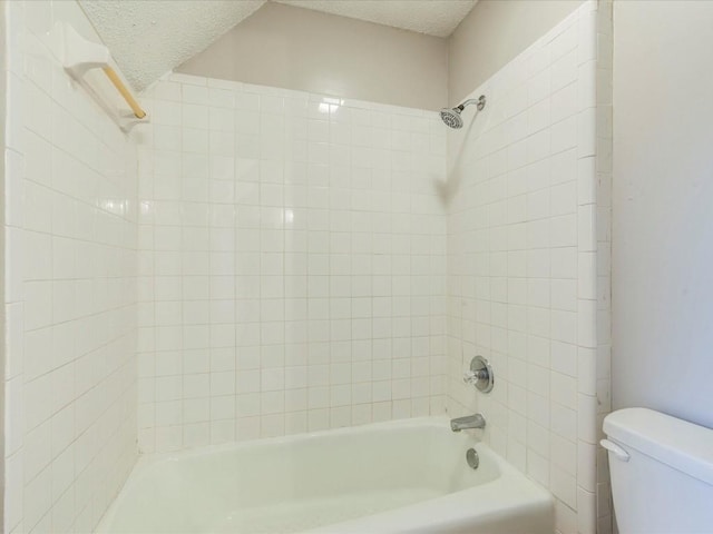 bathroom with tiled shower / bath, a textured ceiling, and toilet