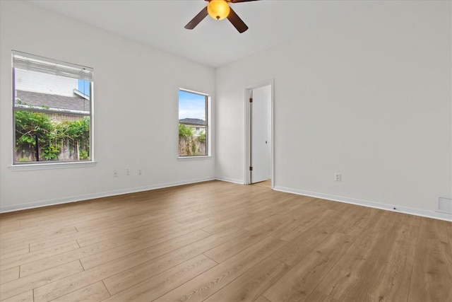 spare room with light wood-type flooring, ceiling fan, and a healthy amount of sunlight